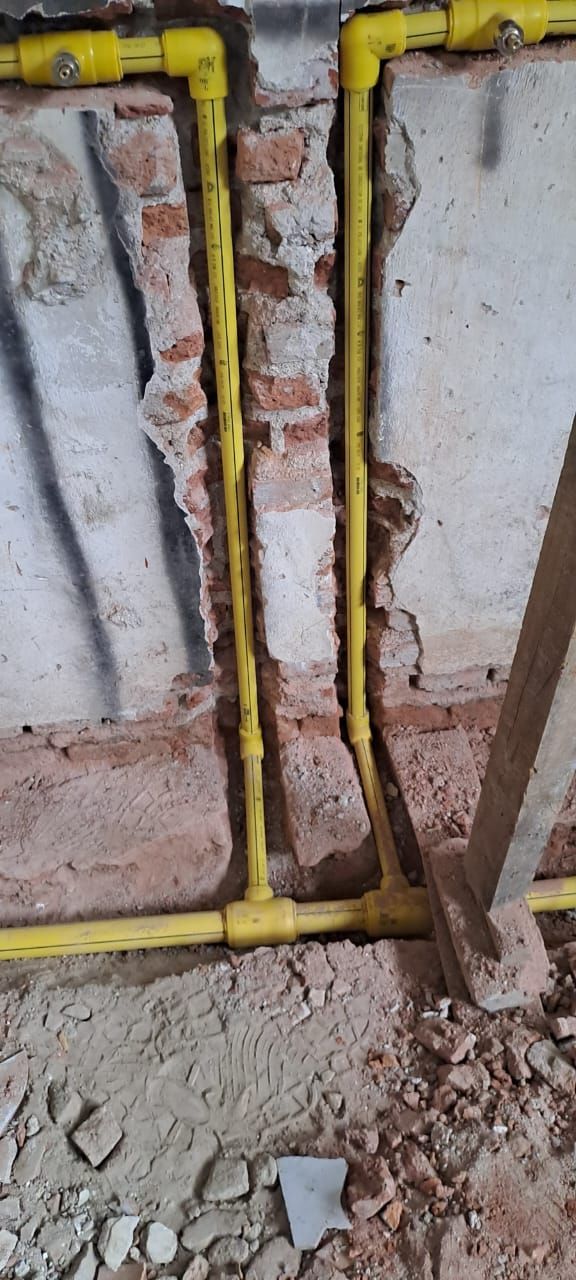 Tuberías amarillas contra una pared de ladrillo y hormigón. Obra en construcción.