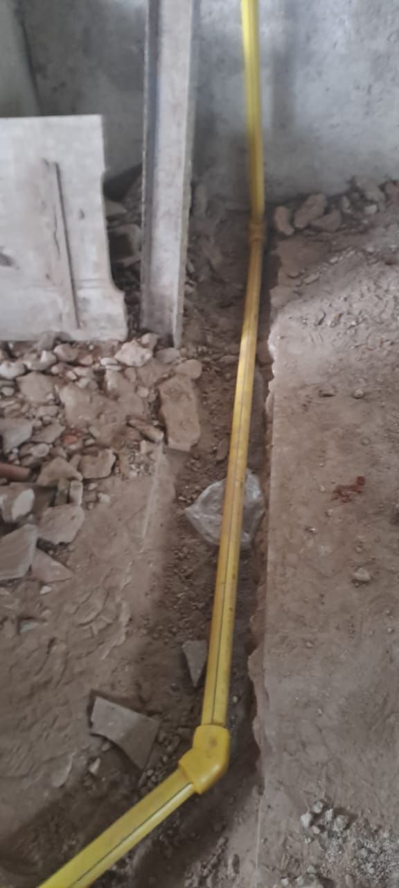Tubería de gas amarilla que corre por una zanja en un área en construcción.