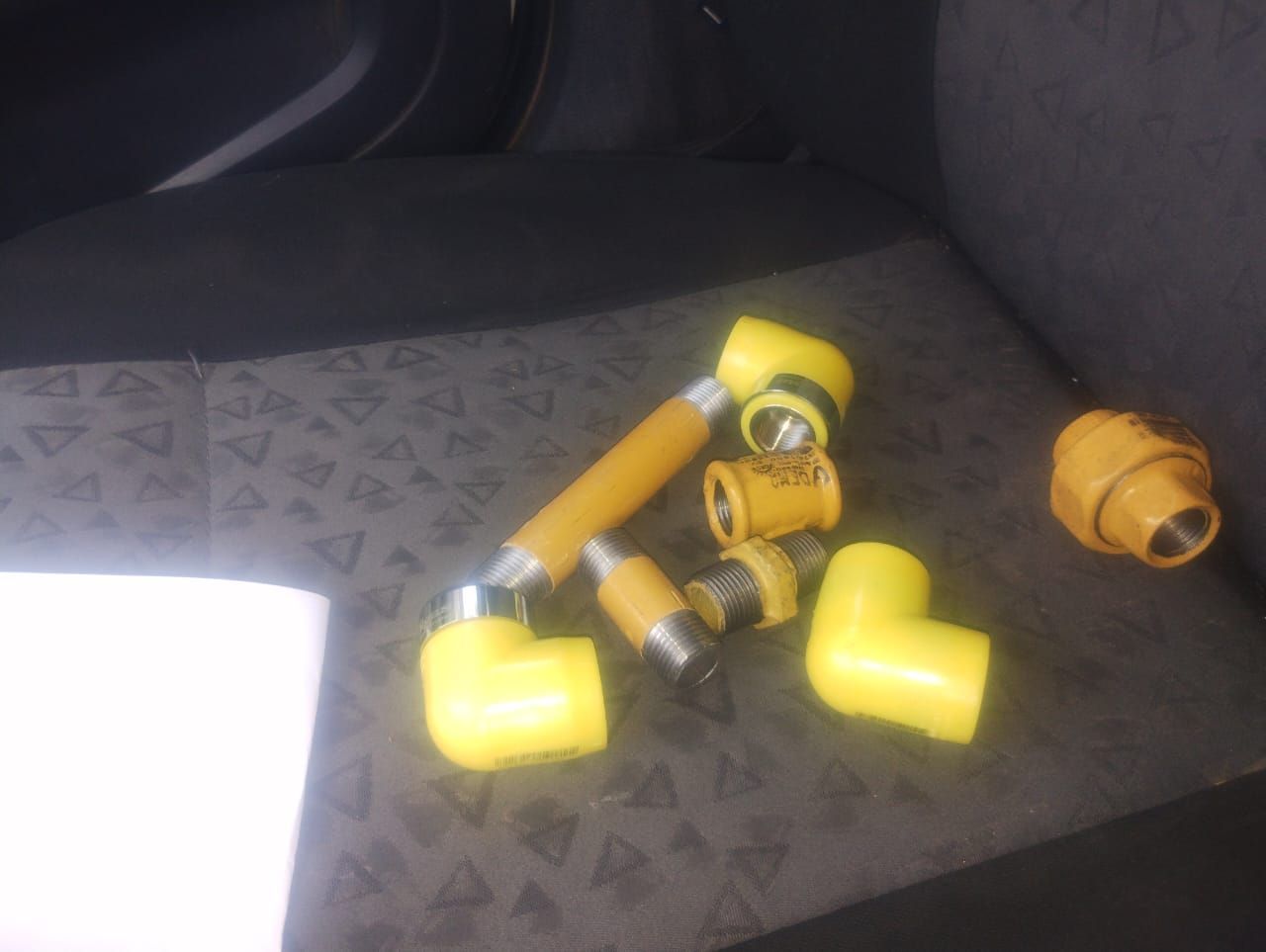 Accesorios de plomería de color amarillo sobre una superficie con dibujos grises, probablemente en un vehículo.