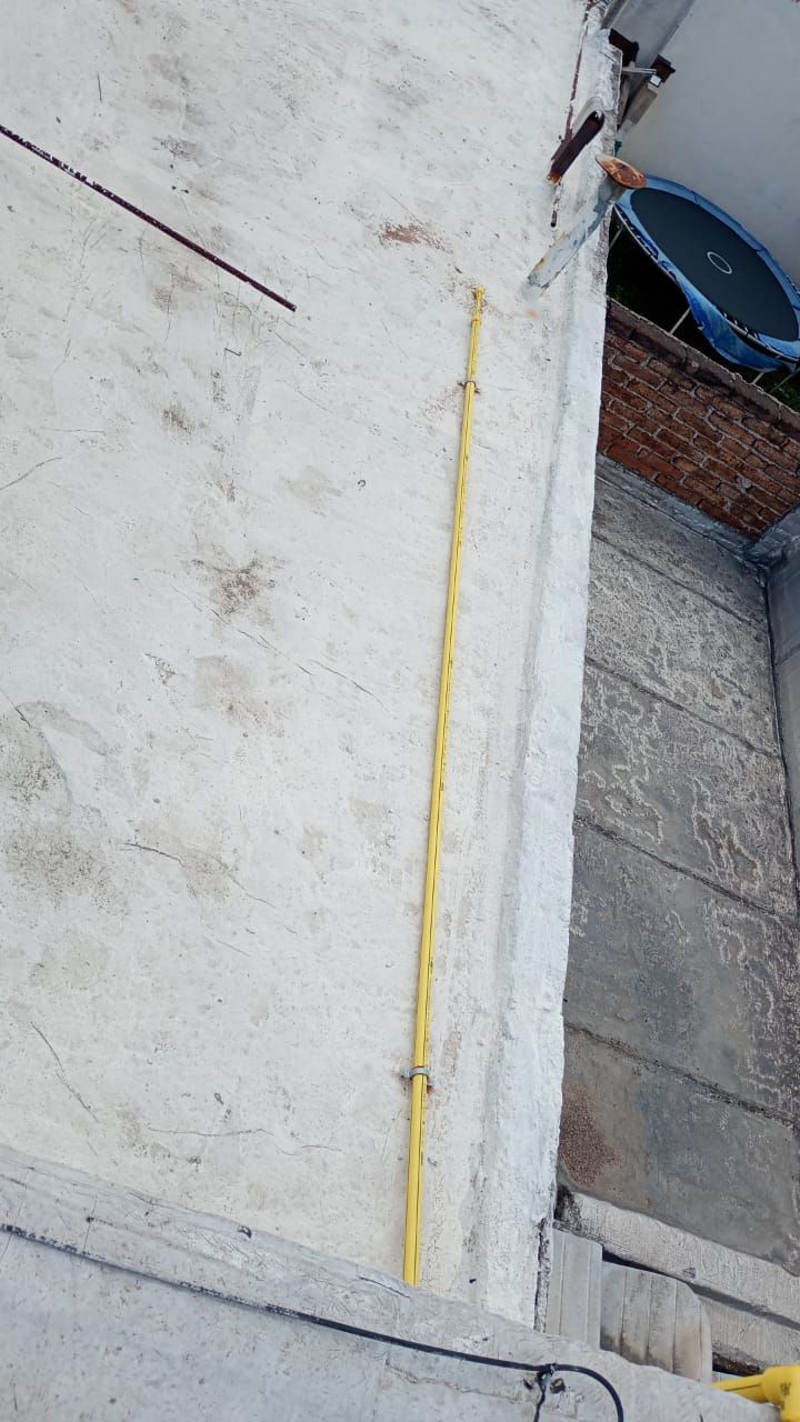 Conducto eléctrico amarillo fijado a una pared de hormigón con clips metálicos.