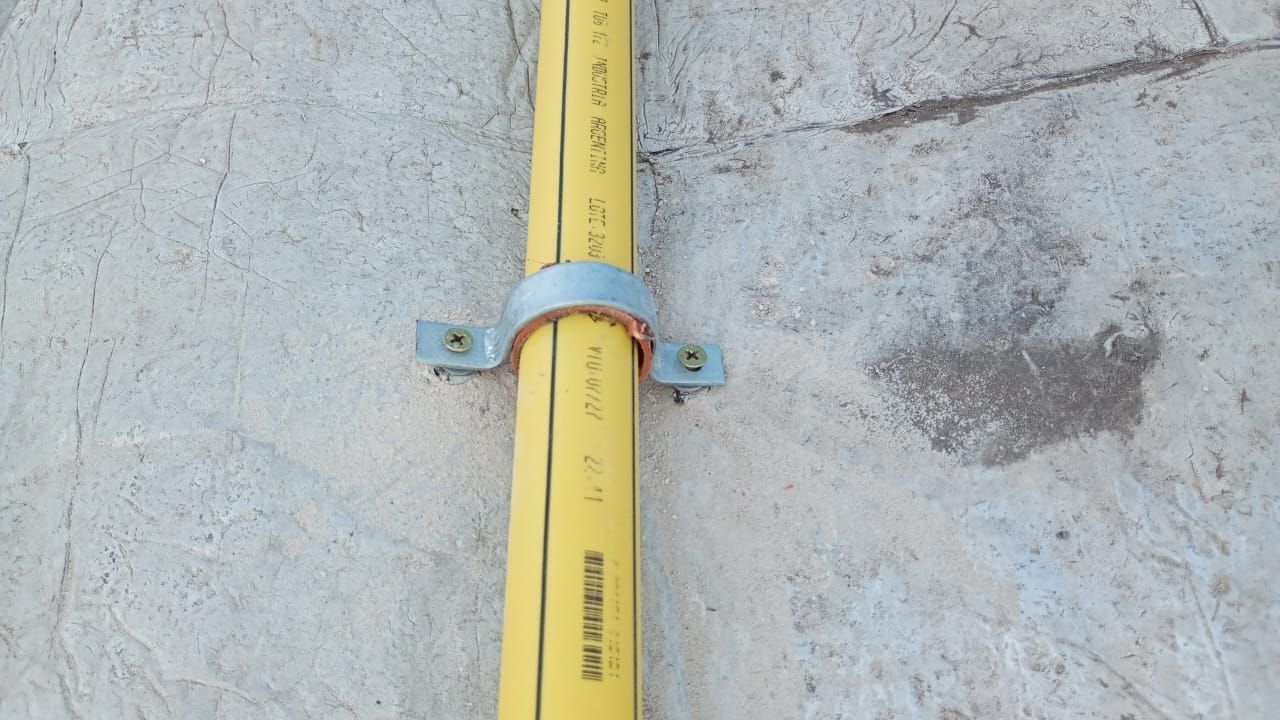Tubo amarillo fijado a una pared de hormigón con una abrazadera de metal.