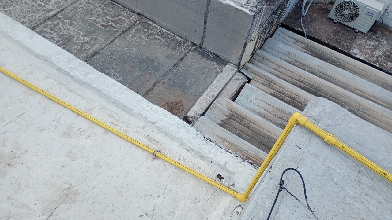 Pasamanos amarillo a lo largo de unas escaleras de hormigón que bajan desde una plataforma.