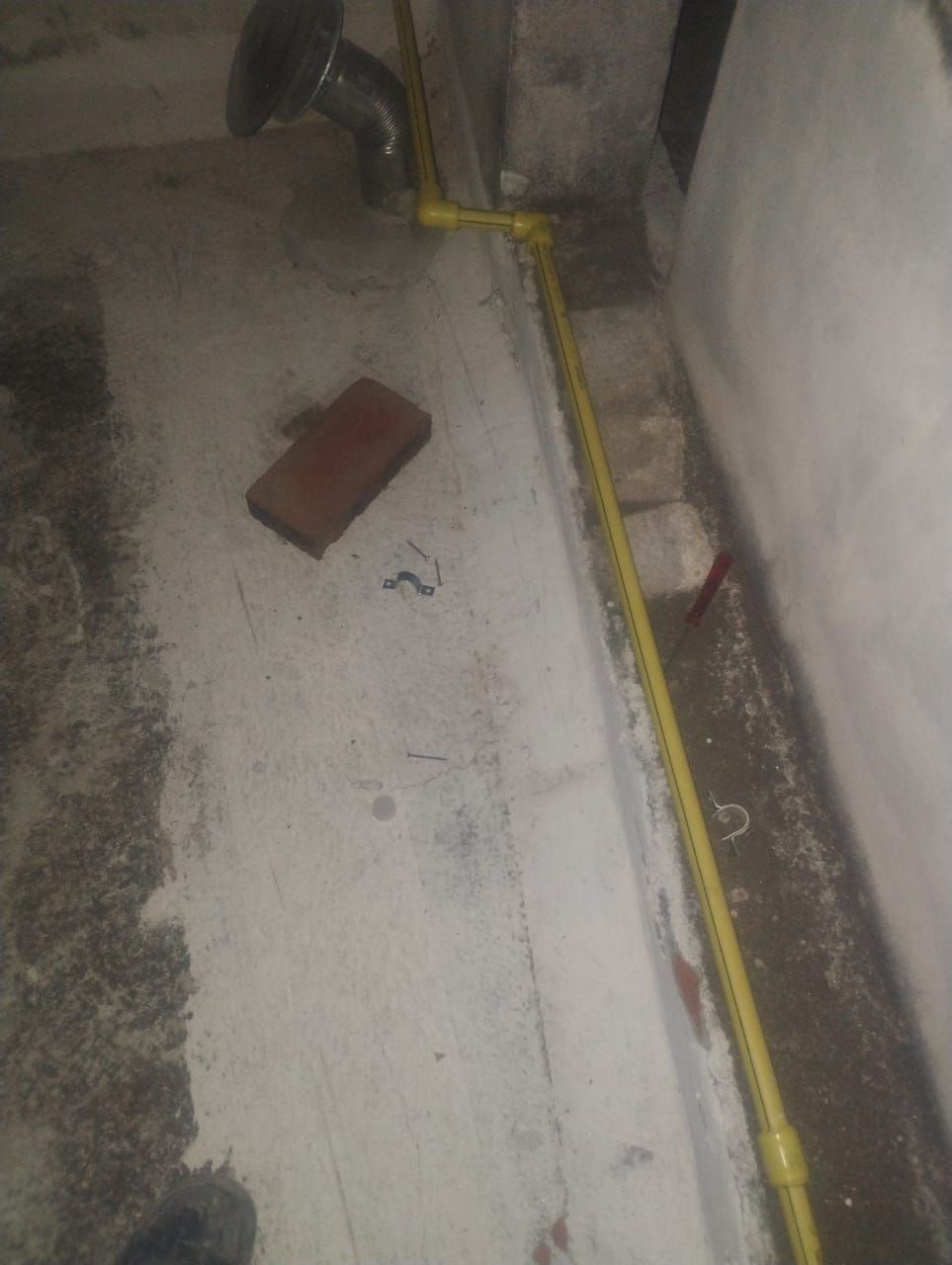 Tuberías de gas amarillas recorren una pared y un suelo de hormigón.