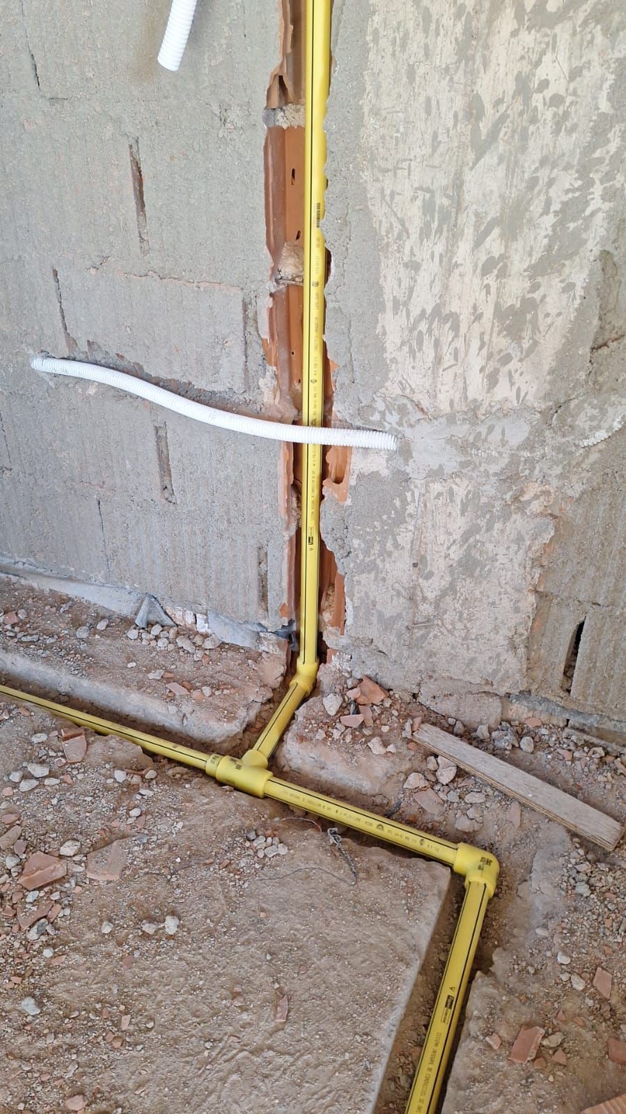 Conducto eléctrico de color amarillo instalado en una pared, ramificándose horizontal y verticalmente.