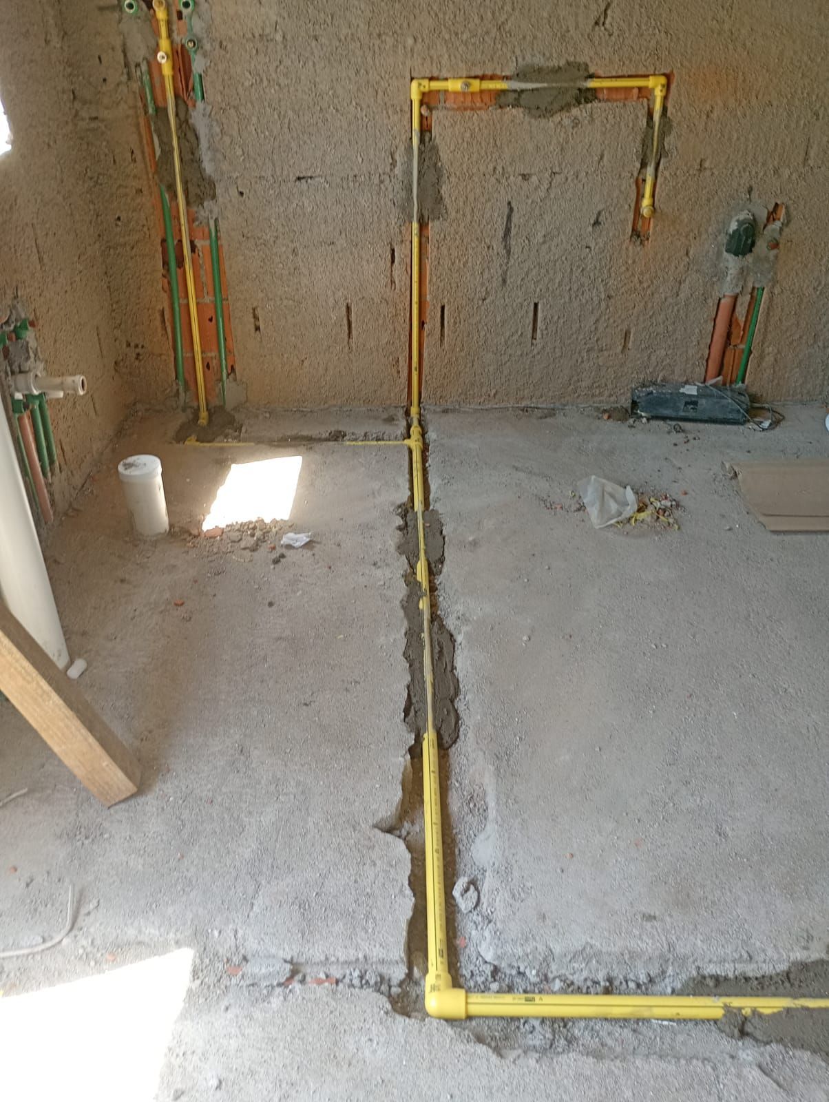 Tuberías de gas de color amarillo instaladas en un piso y pared de concreto, en un entorno de construcción.