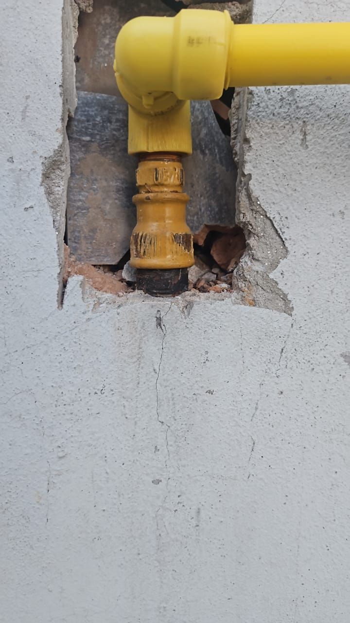 Tuberías de gas de color amarillo conectadas a una pared, que emergen de una abertura dañada.