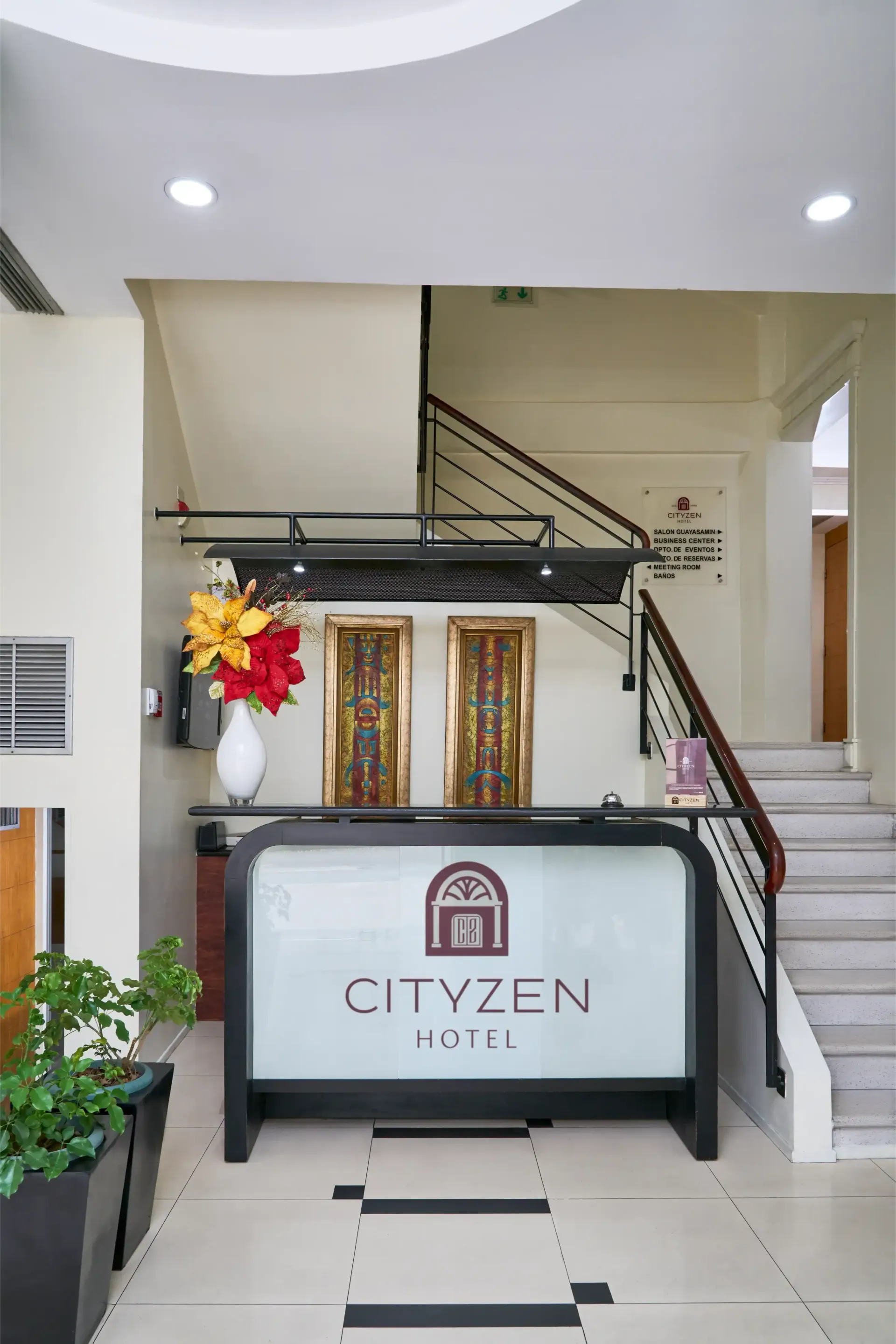 A hotel lobby with a reception desk and stairs.