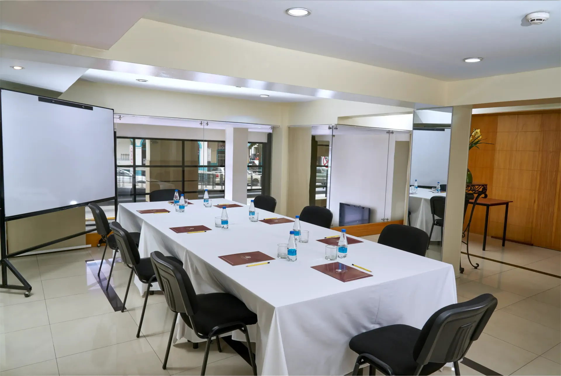 A conference room with a long table and chairs and a projector screen.