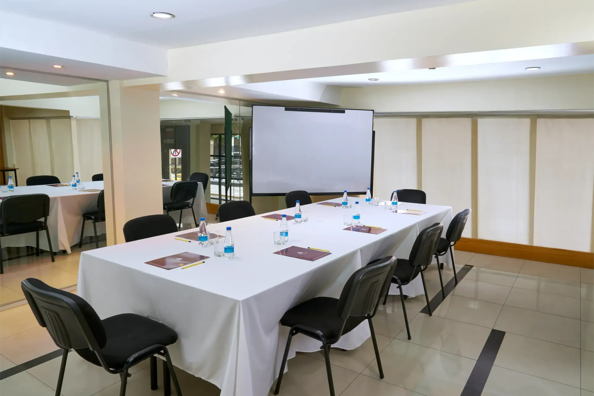 A conference room with a long table and chairs and a projector screen.