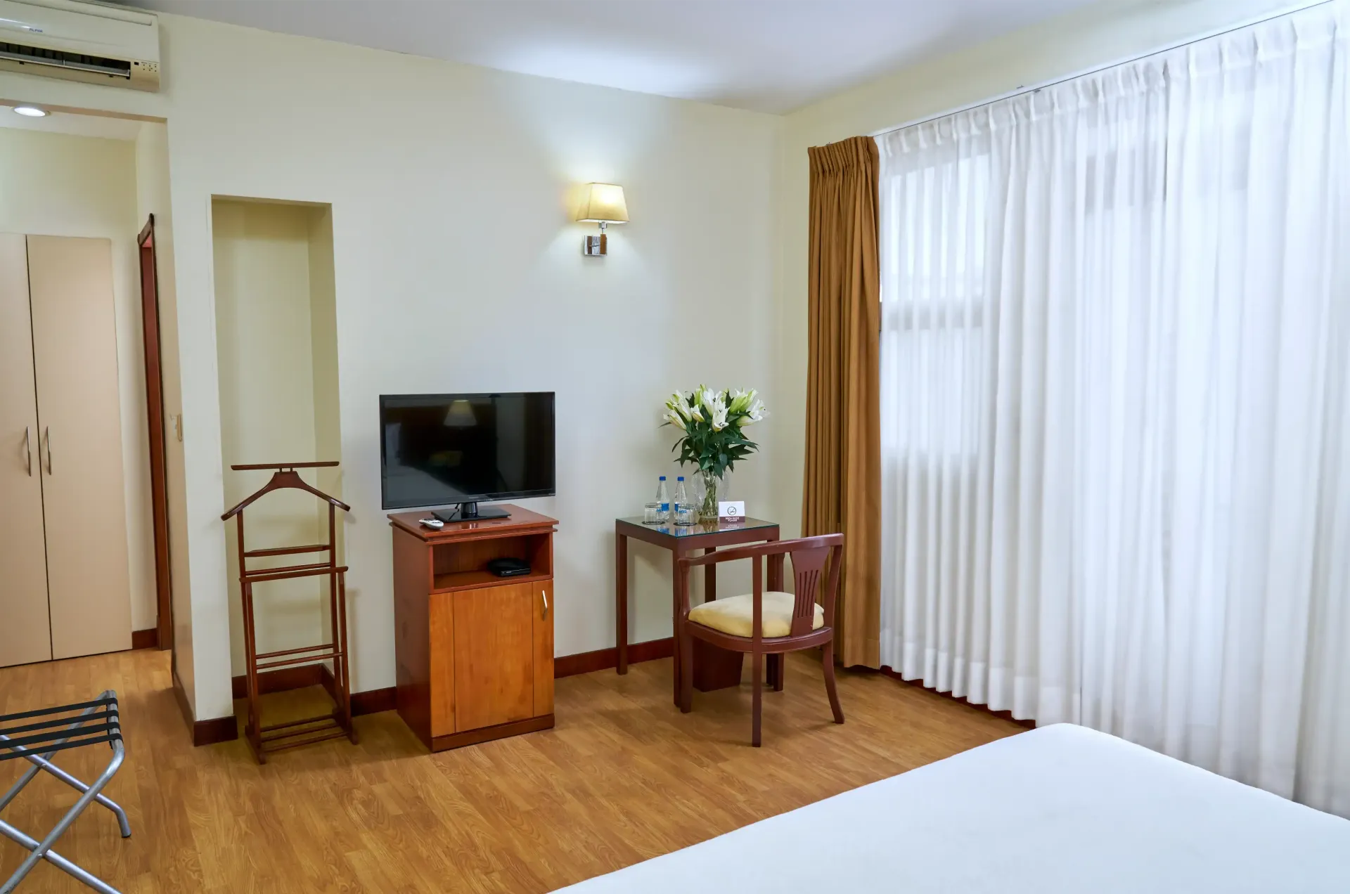 A hotel room with a bed , desk , chair and television.
