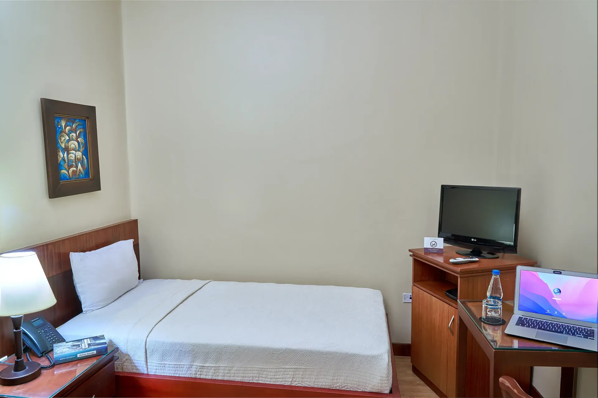 A hotel room with a bed , desk , computer and laptop.