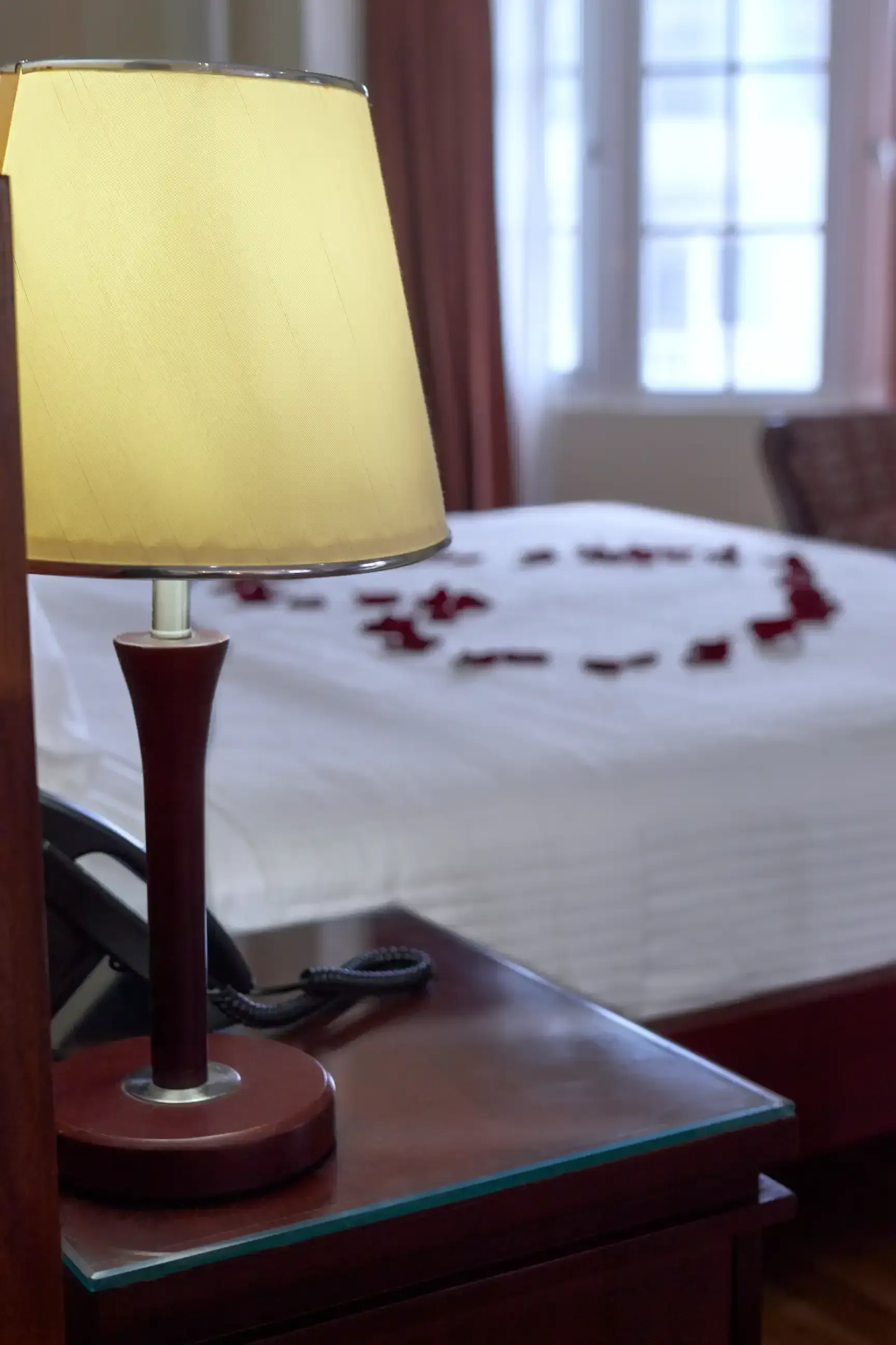 A lamp sits on a nightstand next to a bed