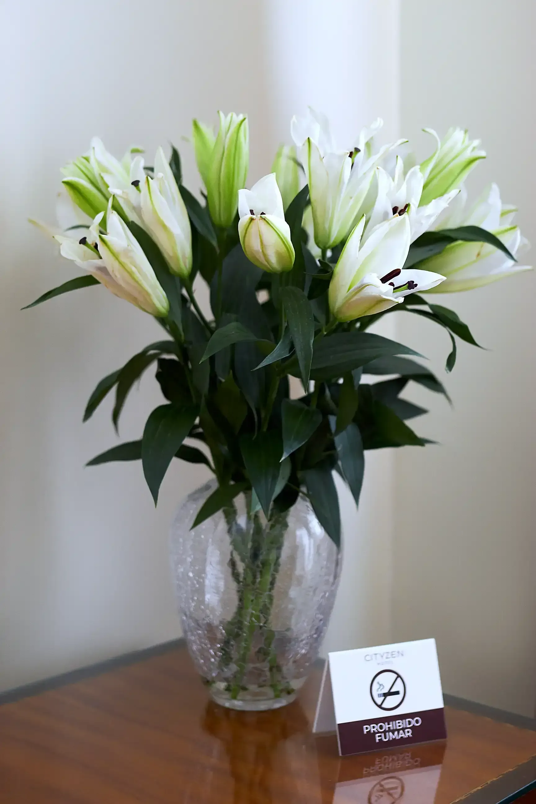 A vase filled with white flowers is sitting on a wooden table.