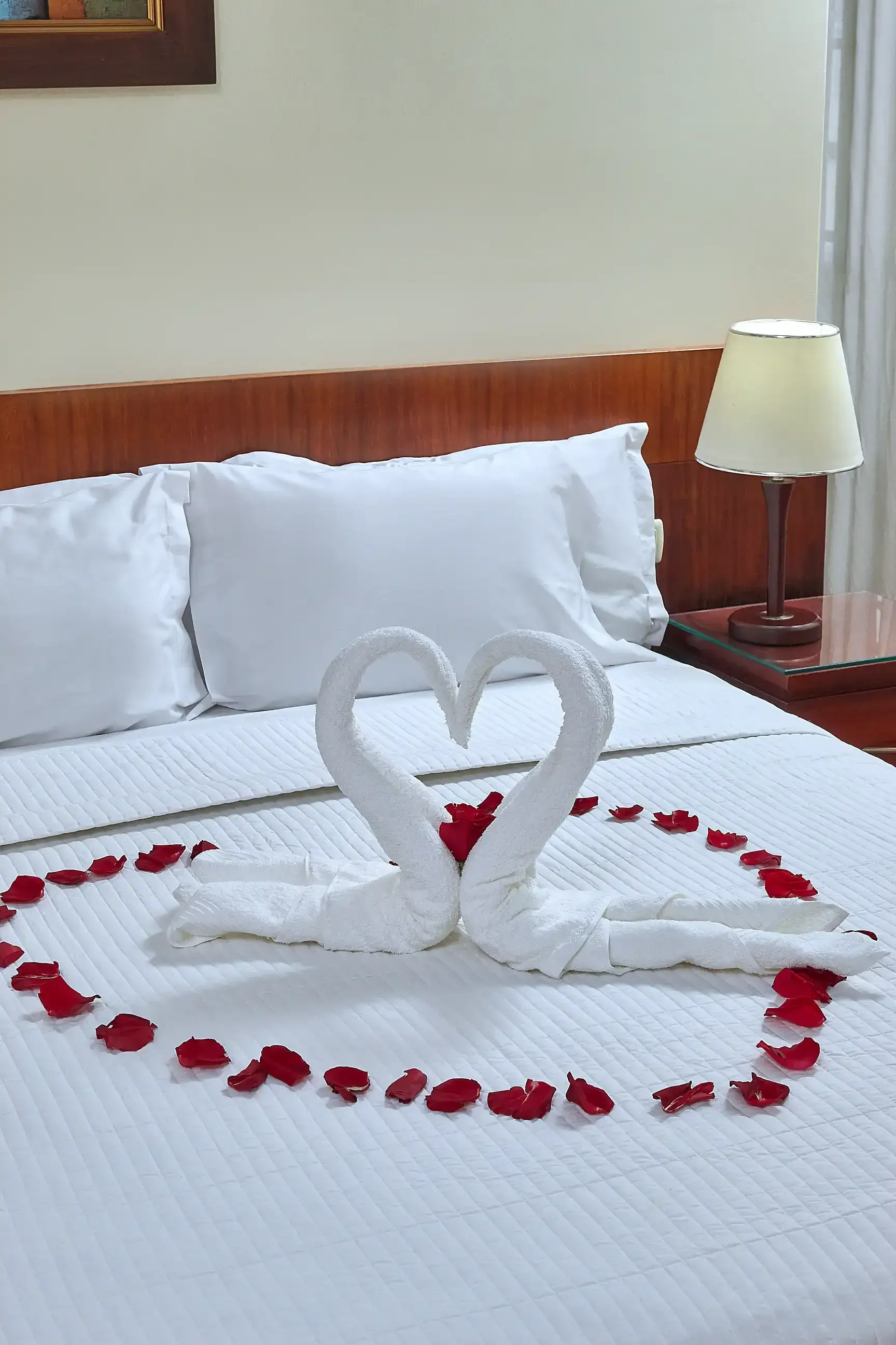 A bed with a heart made out of towels and rose petals