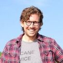 A man wearing glasses and a plaid shirt is smiling for the camera.