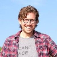 A man wearing glasses and a plaid shirt is smiling for the camera.