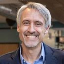 A man with gray hair and a beard is smiling for the camera.