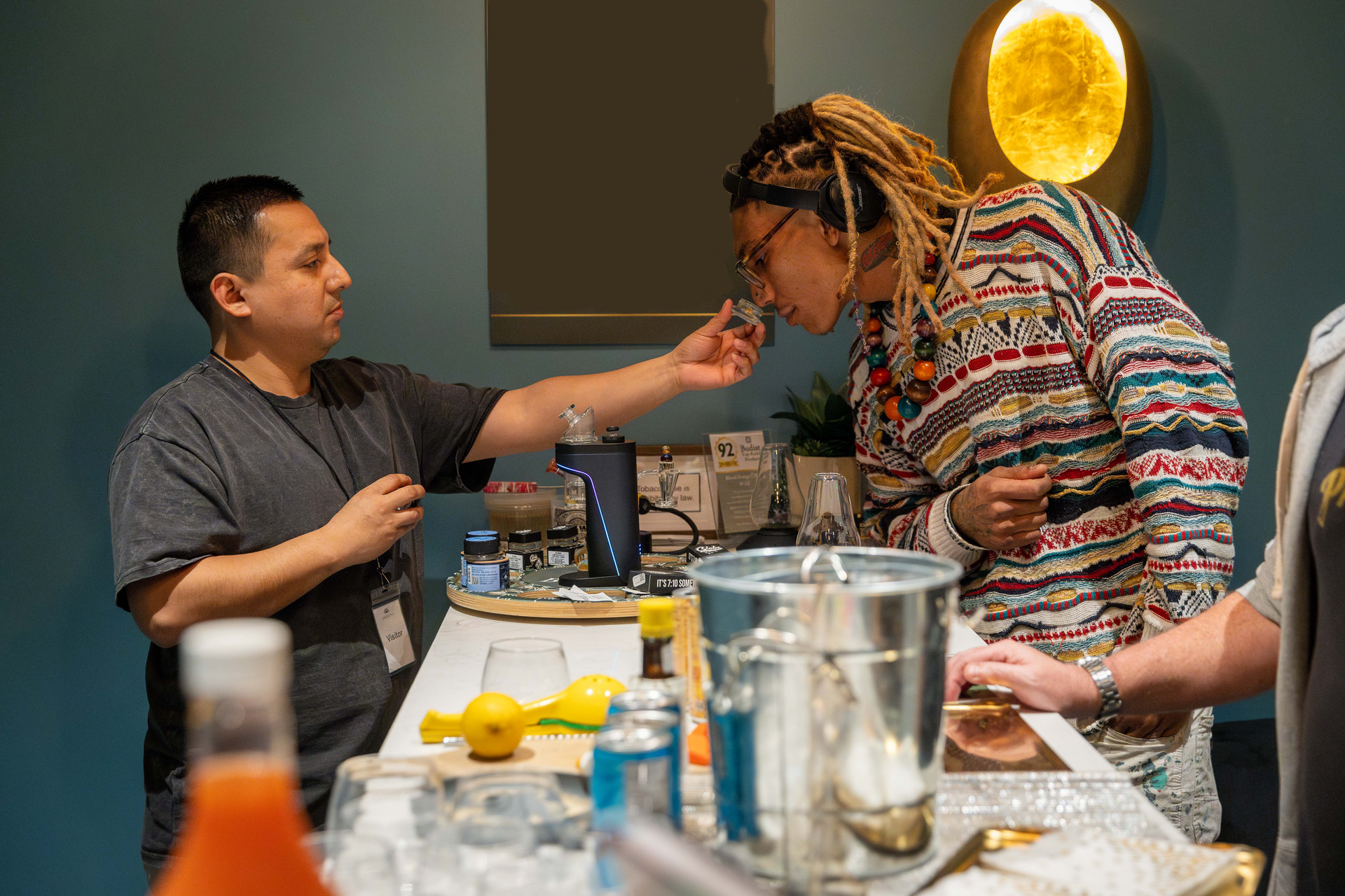 Man offers drink to person smelling it, at a bar.