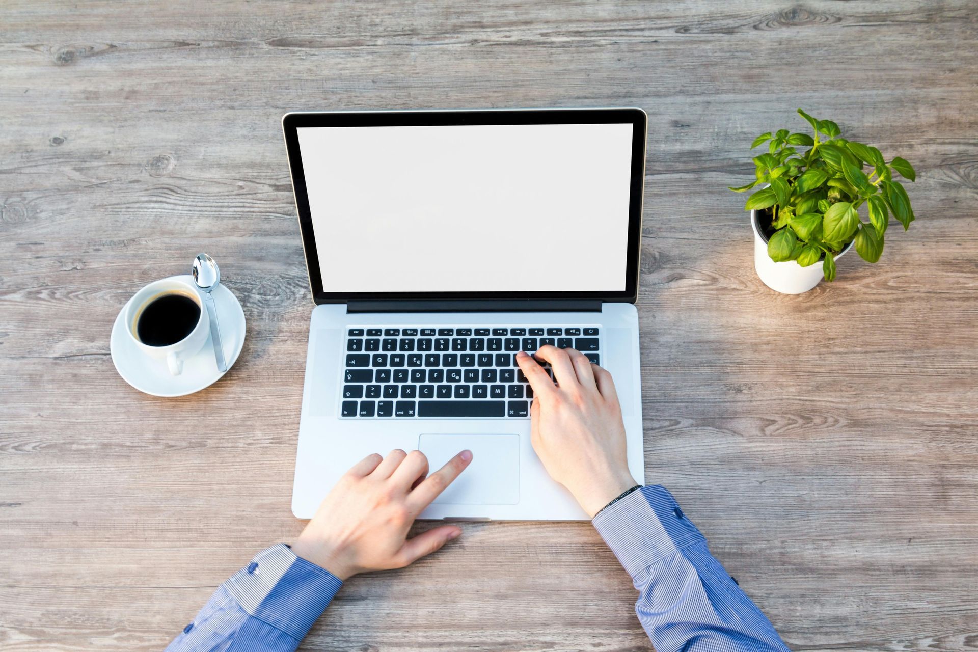 A person is typing on a laptop next to a cup of coffee