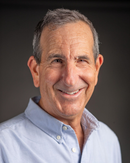 A man in a blue shirt is smiling for the camera