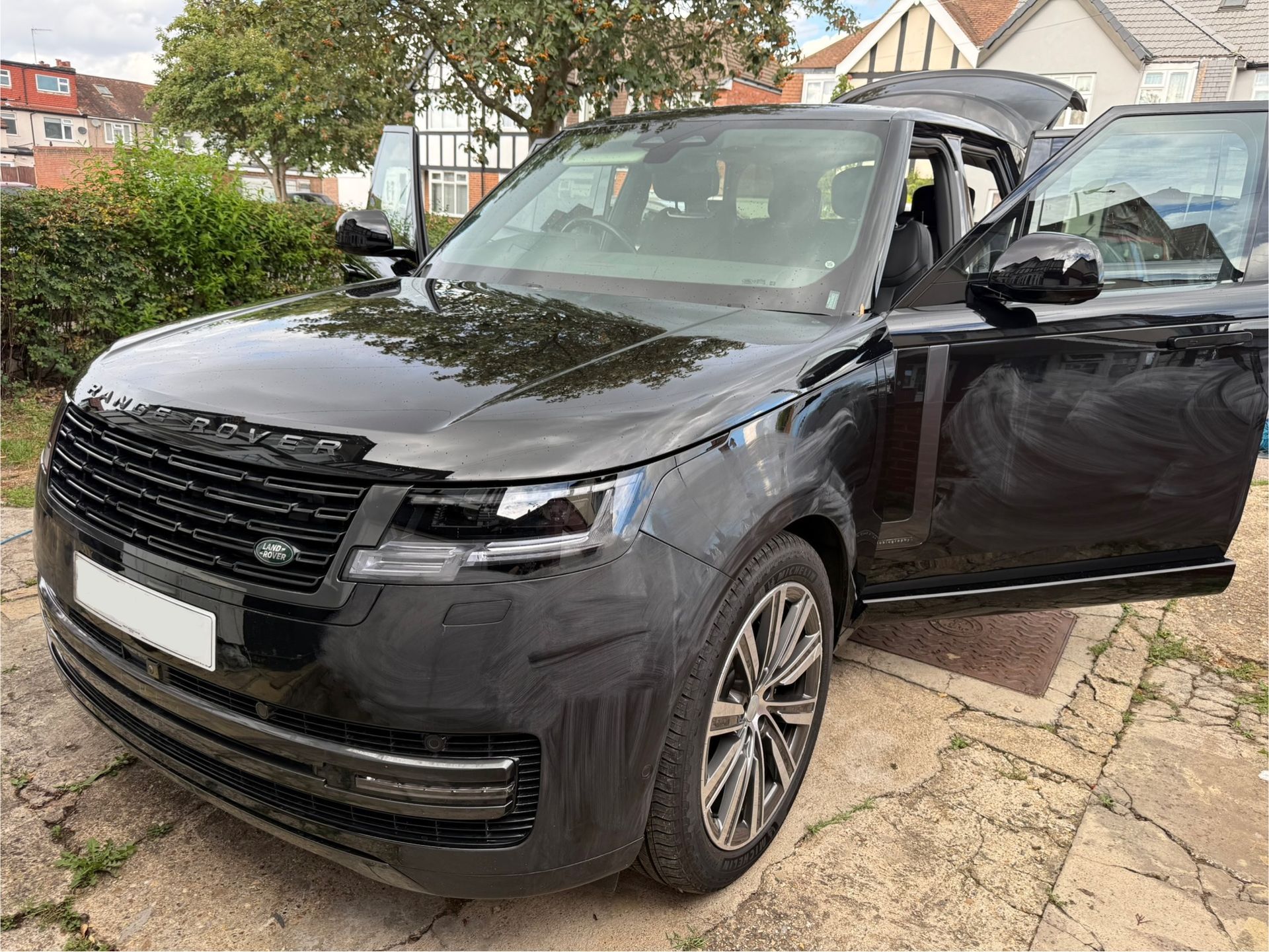 Black Range Rover SUV parked with doors open.