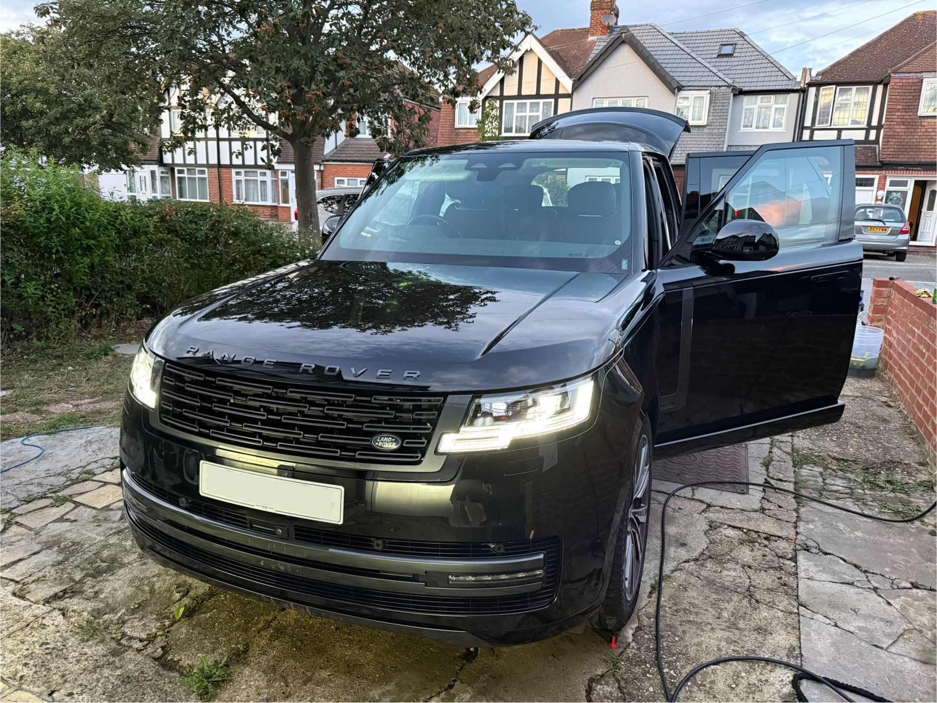 Black Range Rover SUV with open doors parked in a driveway.