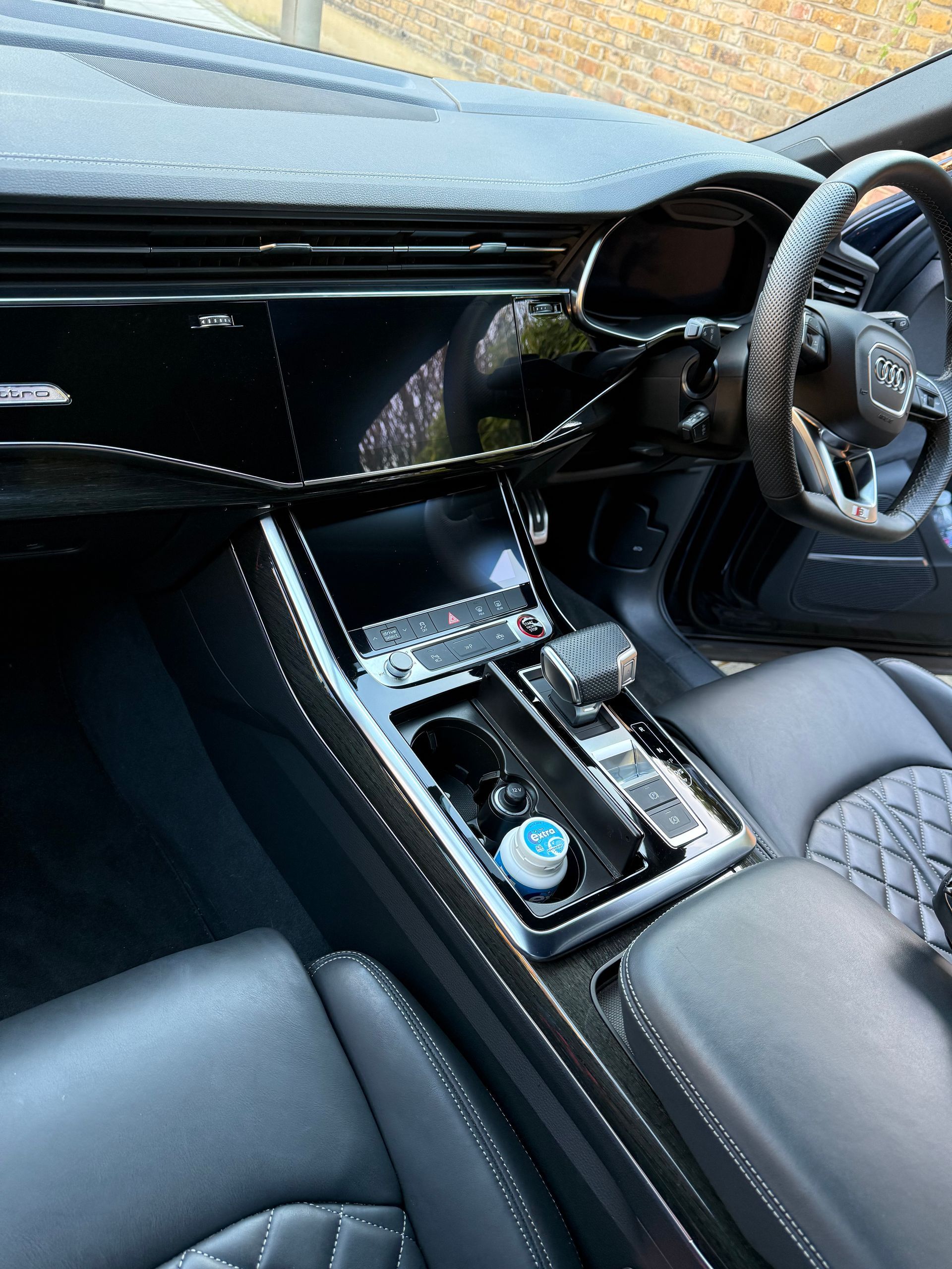 Sleek black car interior with diamond-stitched leather seats, glossy dashboard, and a modern infotainment system.
