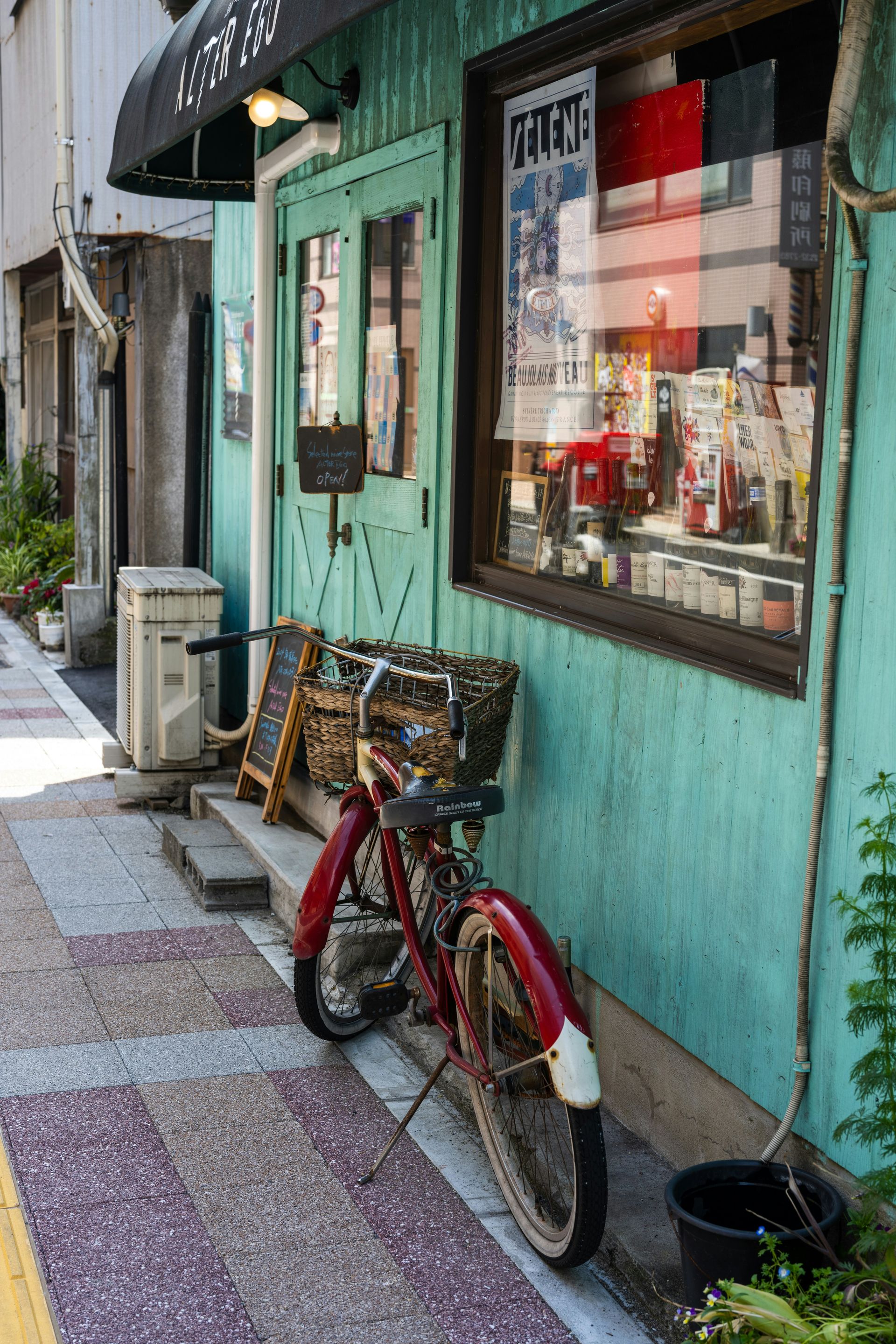 A red bicycle is parked in front of a green building.