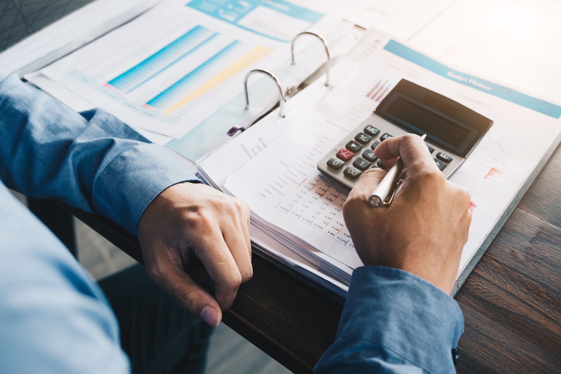 A person is using a calculator while sitting at a desk.