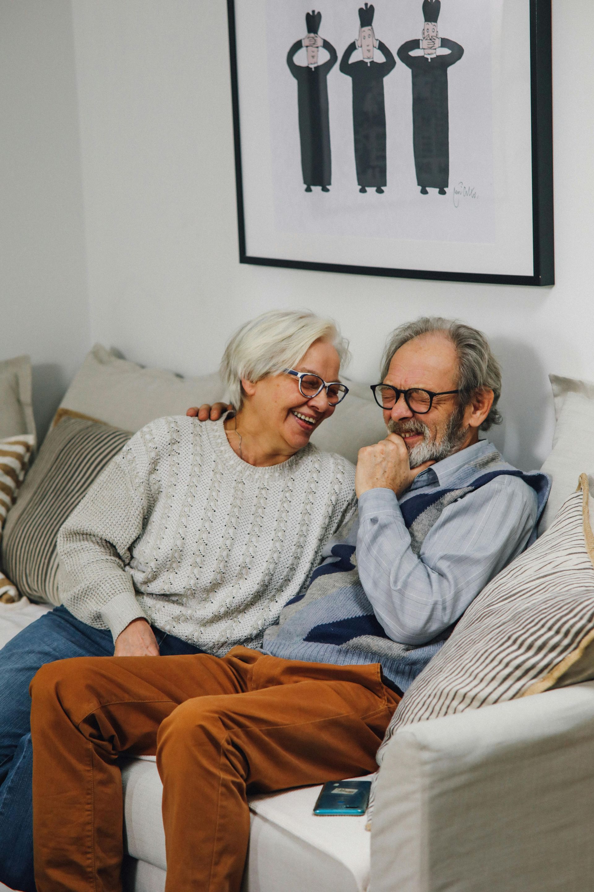 A man and a woman are sitting on a couch and smiling.