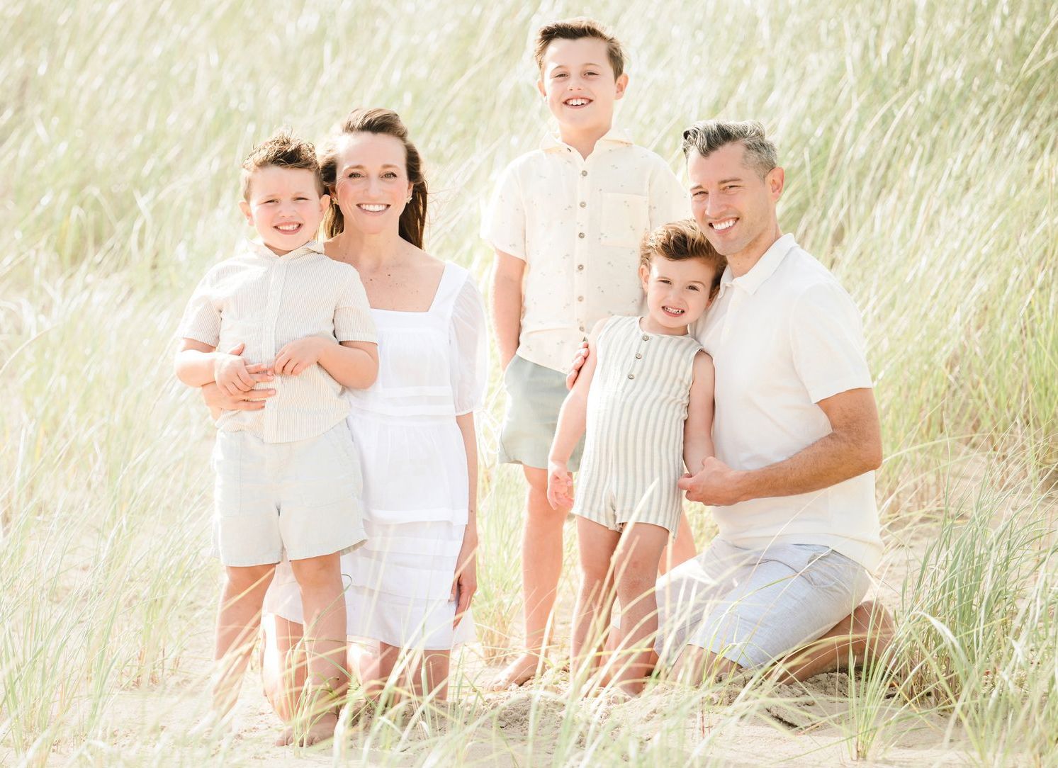 A family is sitting on a bed holding a newborn baby.