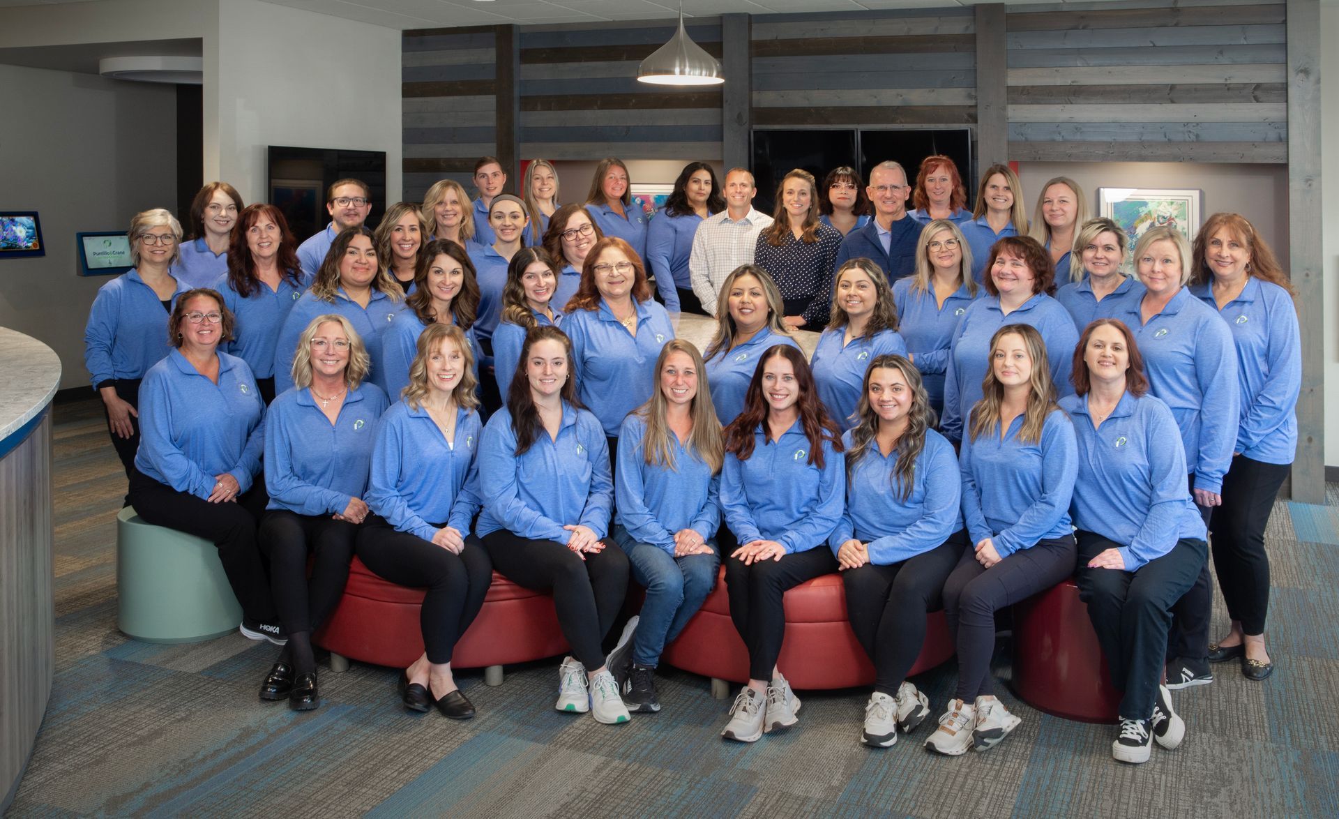 A large group of women in blue shirts are posing for a picture.