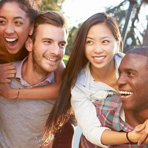 A group of people are posing for a picture and one of them is carrying a woman on his back