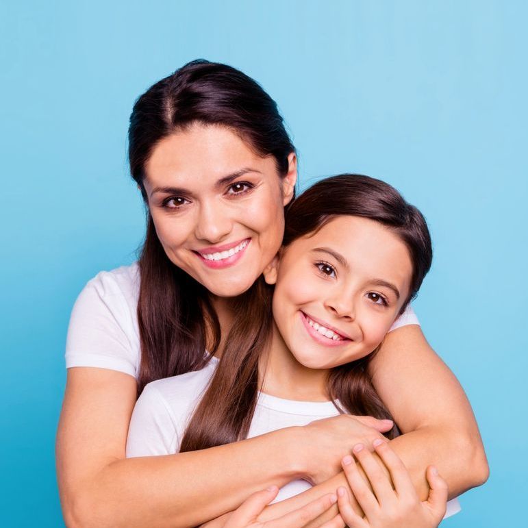 A woman is hugging a little girl on a blue background.