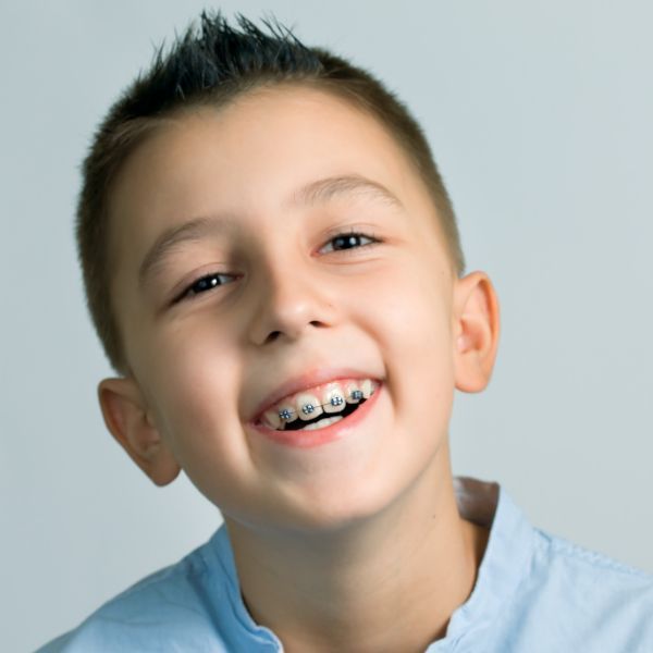 A young boy with braces on his teeth smiles for the camera