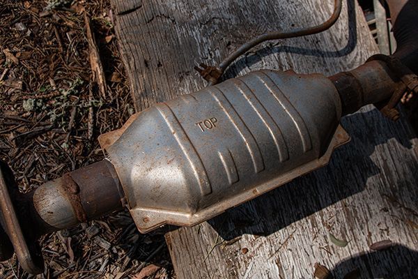 Catalytic converter on wooden surface, showing rust and