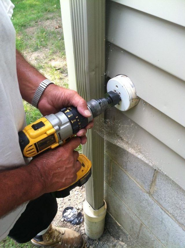 A Man is Using a Drill to the Side of a House - Youngstown, OH - Radon Raiders