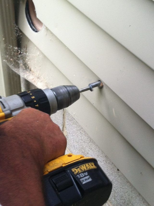 A Man is Using a Drill to Drill a Small Hole - Youngstown, OH - Radon Raiders