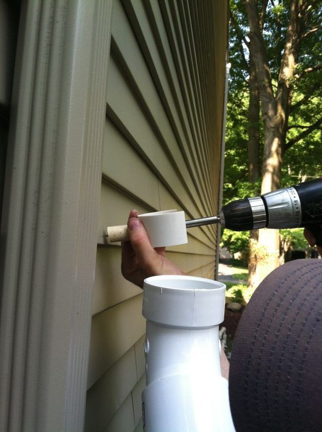 A Person is Using a Drill to Attached the Pipe to the Side of the House - Youngstown, OH - Radon Raiders