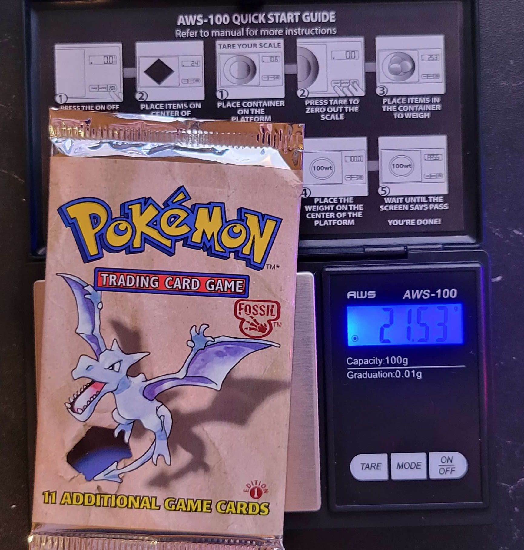 a 1st edition Pokémon fossil booster pack sitting on a scale weighing 21.53 grams