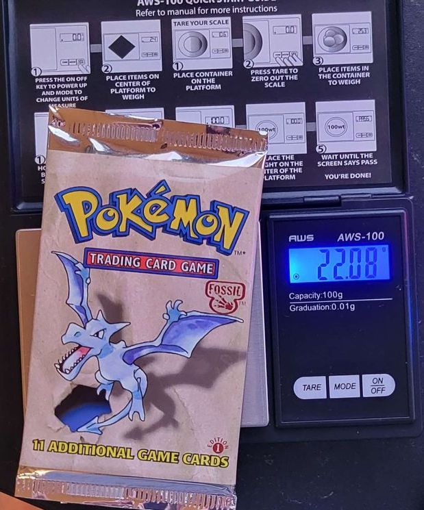 a 1st edition Pokémon fossil booster pack sitting on a scale weighing 22.08 grams