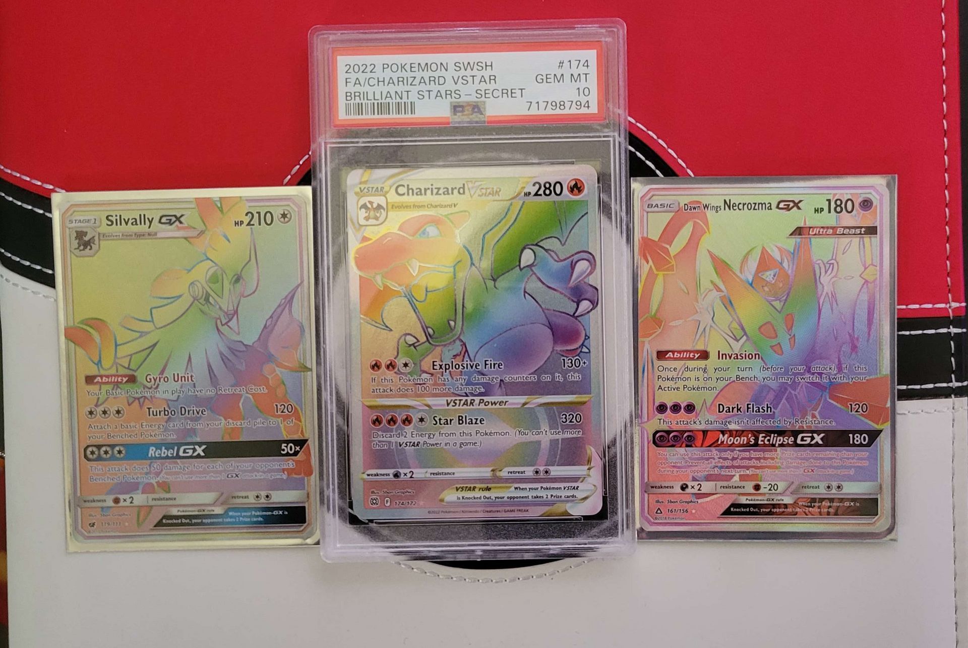 a psa 10 rainbow charizard vstar Pokémon card sitting between two rainbow rare Pokémon cards