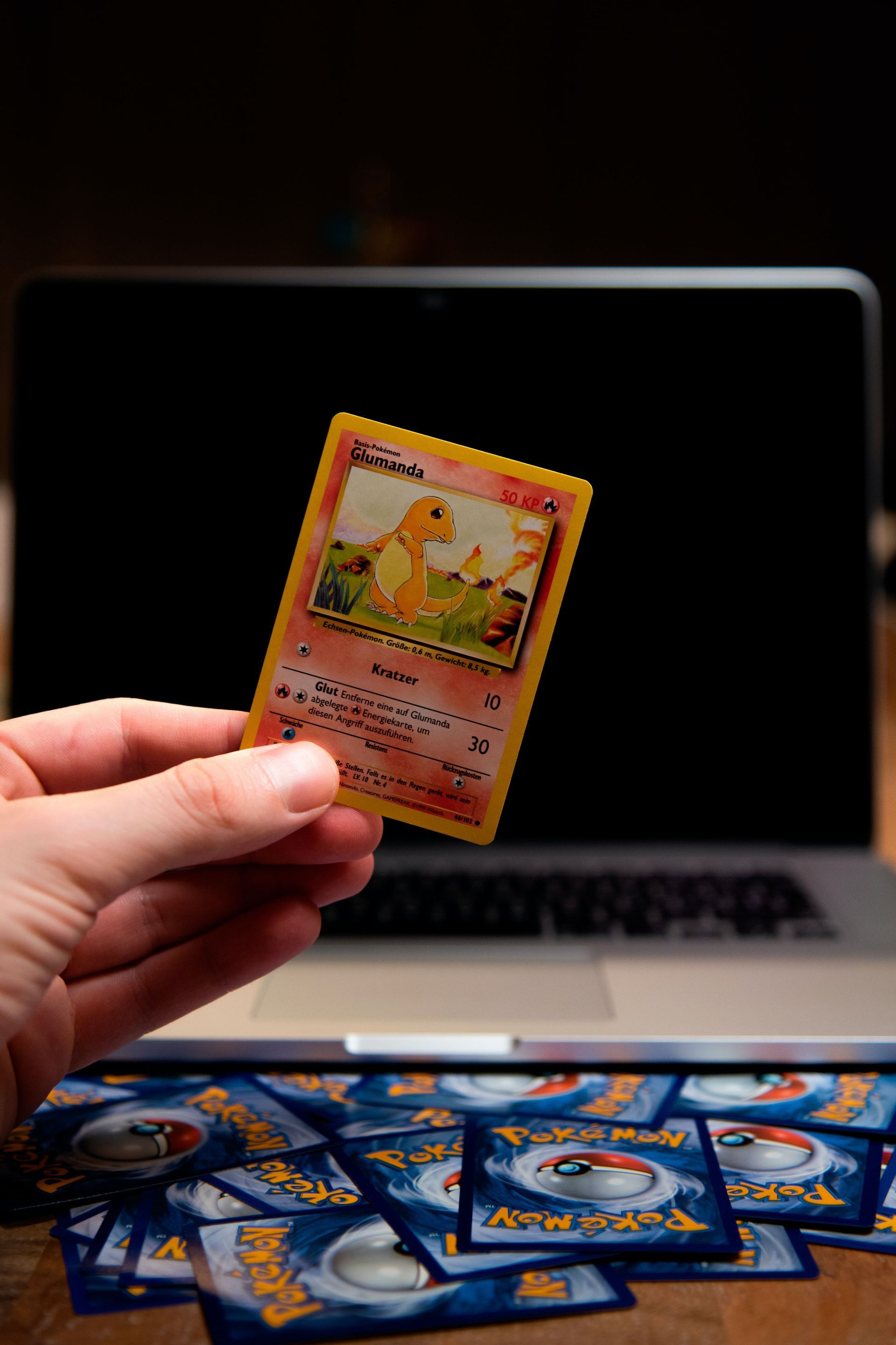 Man holding Pokémon card in front of a laptop