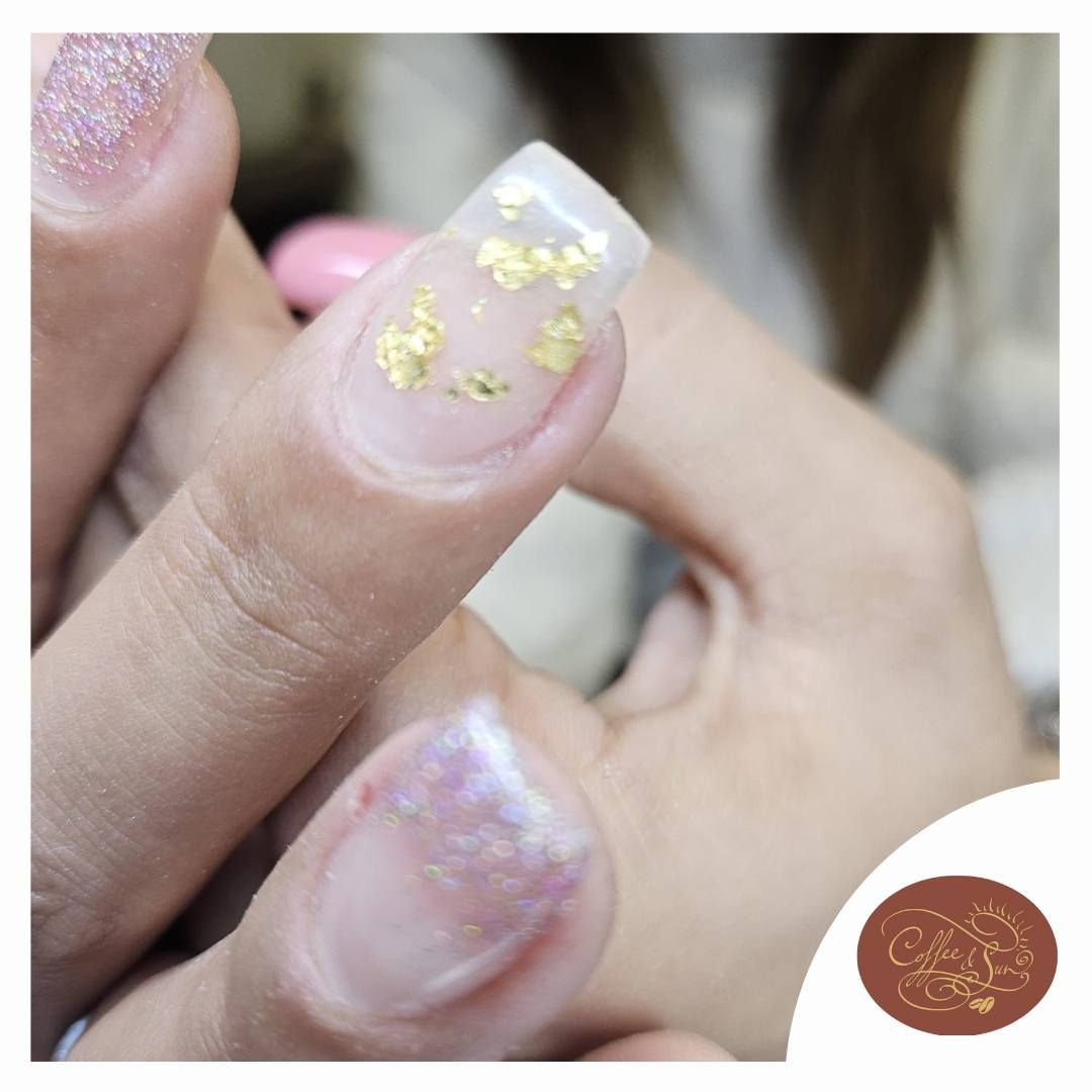 Un primo piano delle unghie di una donna con scaglie d'oro su di esse
