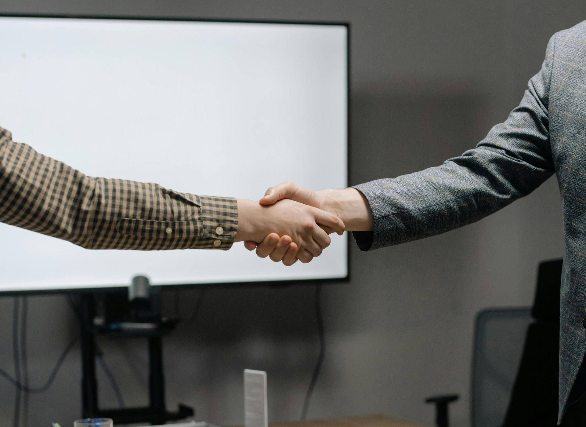 Due persone si stringono la mano in una sala conferenze davanti a una lavagna.