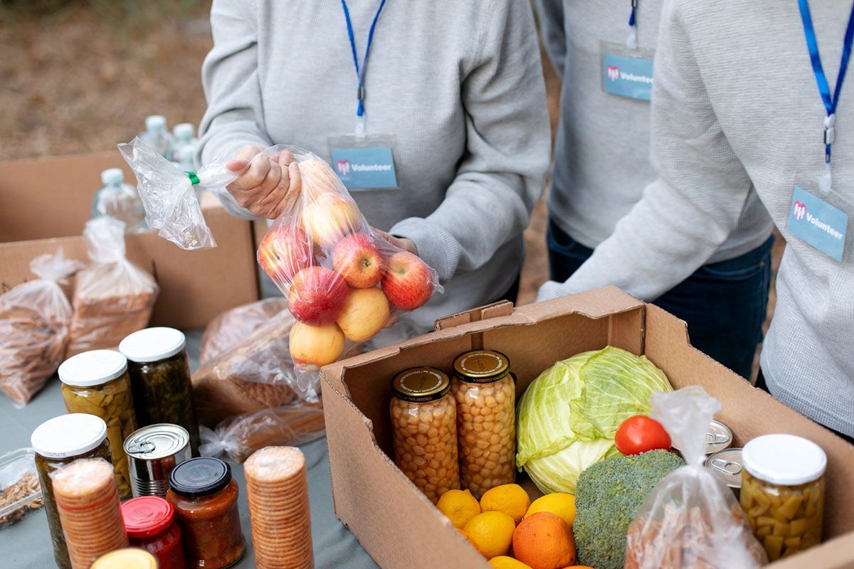 A couple of people are standing next to each other holding bags of fruit and vegetables.