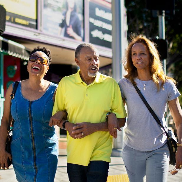 A man in a yellow shirt is walking with two women