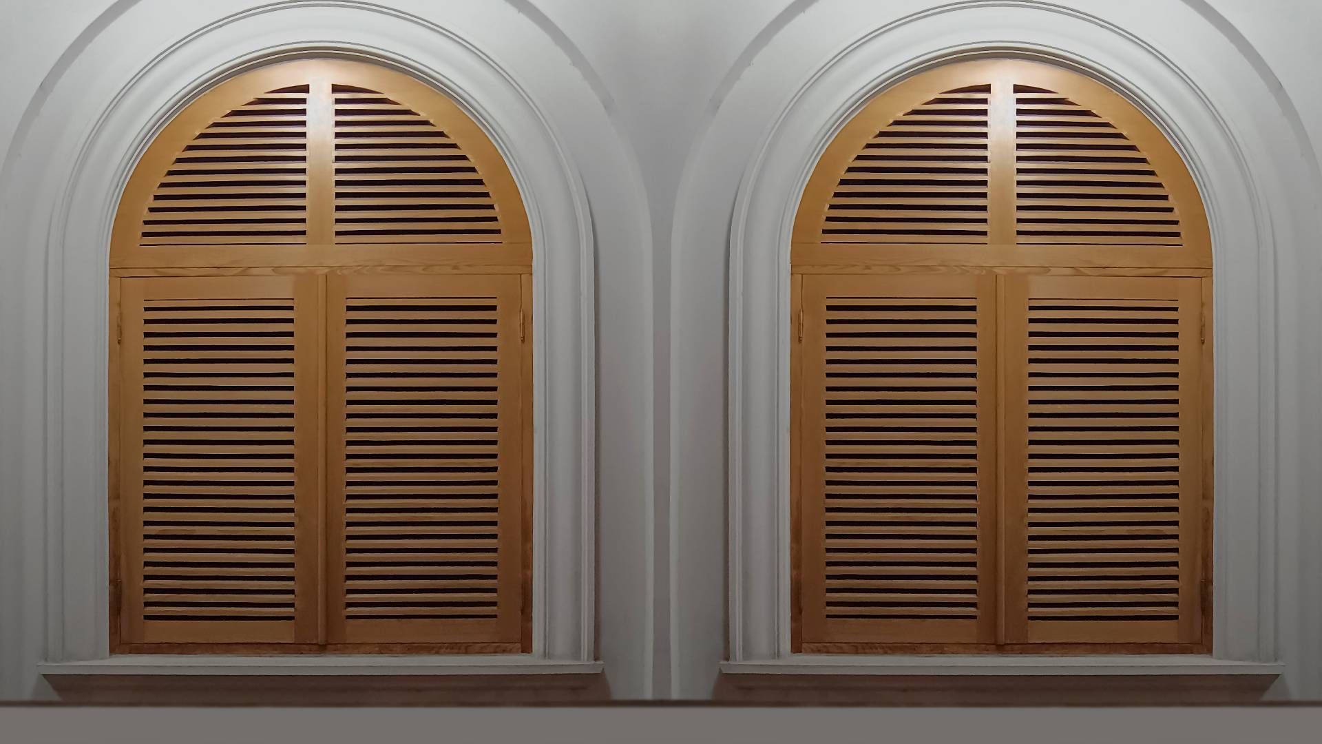 A pair of arched window blinds in a room near Manchester, NH