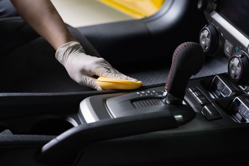A person wearing gloves is cleaning the interior of a car.