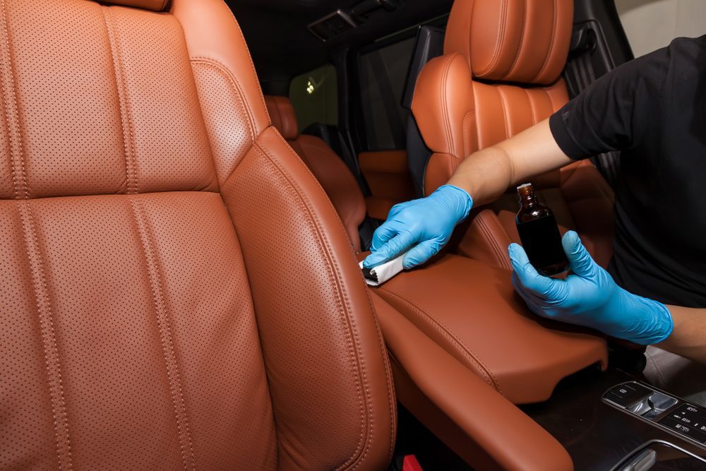 A person is cleaning the leather seats of a car.
